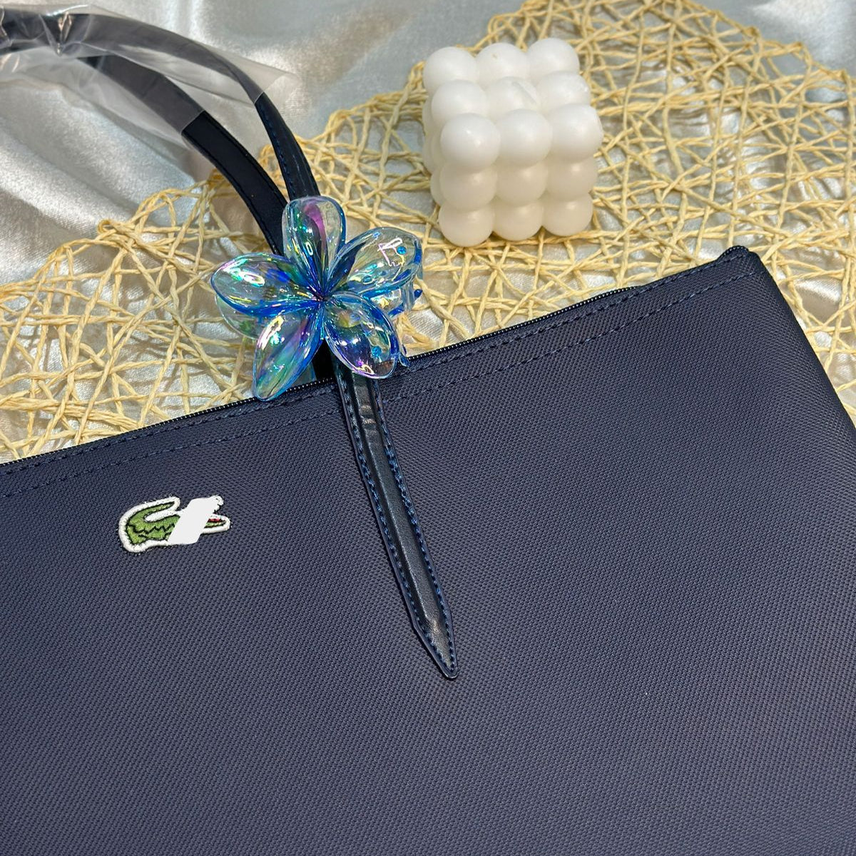 Navy blue handbag with a decorative blue flower clasp on a textured surface