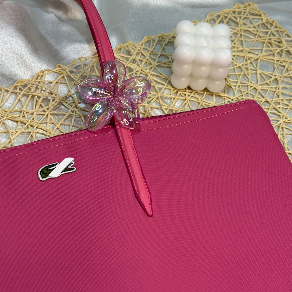Pink handbag with a decorative bow on a textured surface