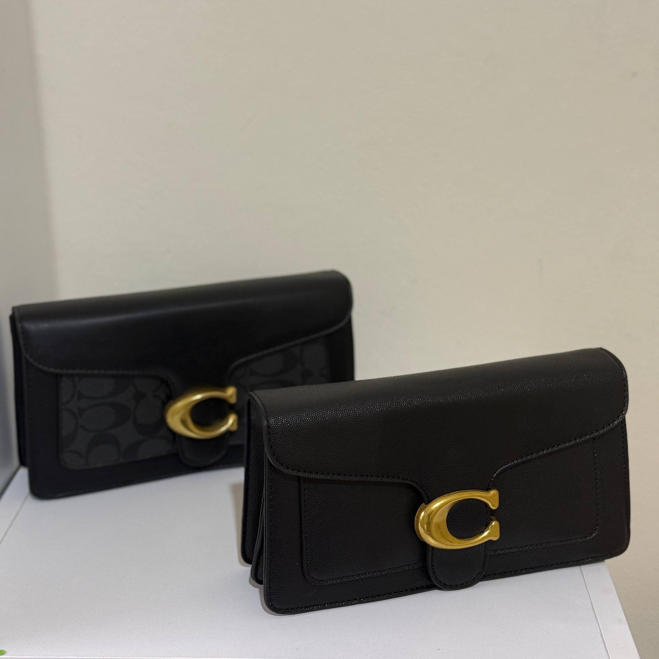 Two black handbags with gold clasp on a white surface